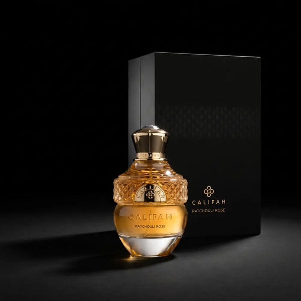 Califah Patchouli Rose Parfum bottle with a textured gold cap and golden amber liquid, positioned in front of a tall black branded box on a dark studio background.