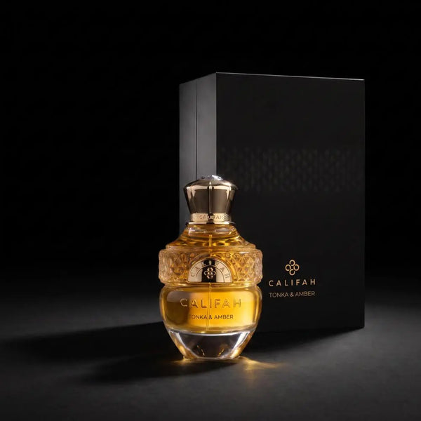 A bottle of Califah Tonka & Amber Parfum with golden amber liquid and a textured gold cap, displayed in front of its black packaging box on a dark background.